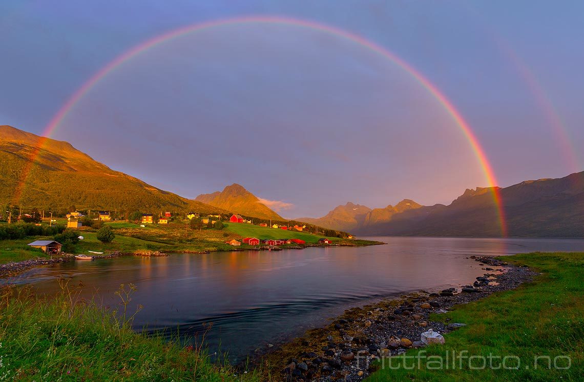 En regnbue i kveldssola rammer inn Åndervåg på Andørja, Ibestad, Troms.<br>Bildenr 20160808-542.
